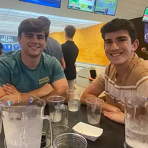 Two young men smile at a bowling alley, with Notre Dame Right to Life shirt visible.